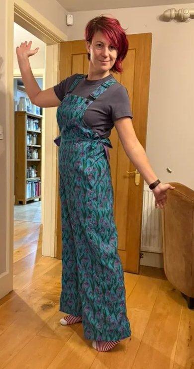 Emily standing in a hallway wearing a pair of teal patterned dungarees she made